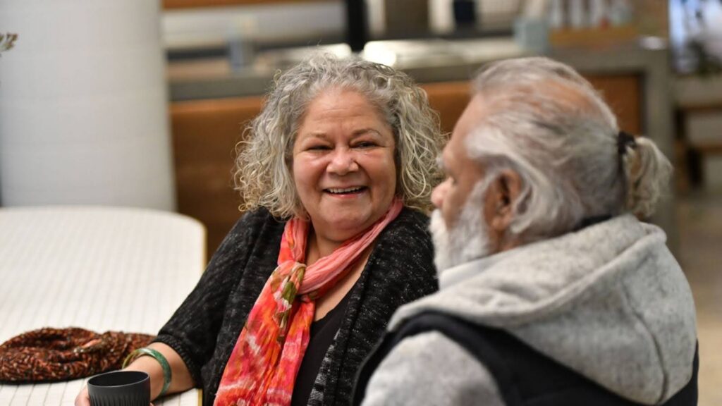 Elderly woman smiling during a social support visit at home in Australia.