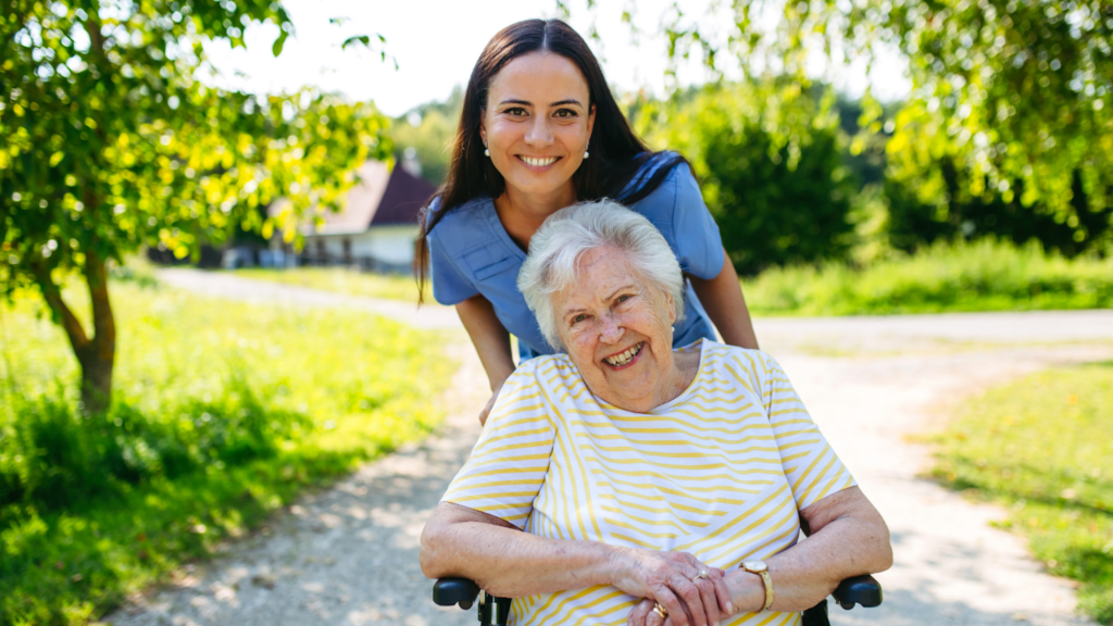 Smiling carer and happy senior woman in wheelchair enjoying outdoor support.